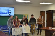 students with posters in front of board